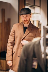 young-handsome-man-choosing-hat-shop_1303-19836